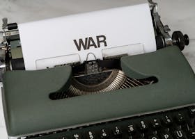 Old typewriter typing the word 'War' on paper, symbolizing conflict and history.