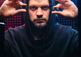 Portrait of a man in a hoodie with a serious expression holding computer keys in a tech-themed studio.